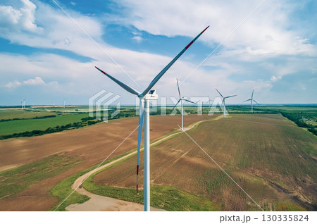 Wind turbines generate renewable energy in a wind farm located in a rural area under a clear sky during daylight hours 130335824