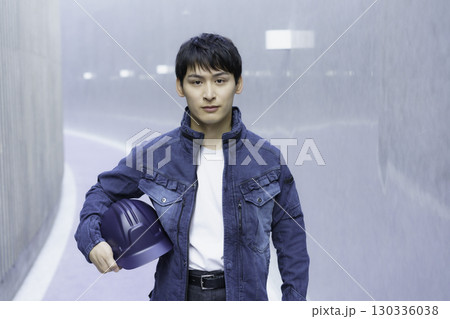 デニムの作業服を着てヘルメットを抱える若い男性のポートレート 130336038