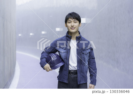 デニムの作業服を着てヘルメットを抱える若い男性のポートレート デニムの作業服を着てヘルメットを抱える若い男性のポートレート 130336046