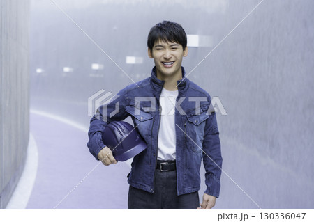 デニムの作業服を着てヘルメットを抱える若い男性のポートレート 130336047