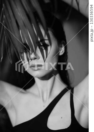 Monochrome portrait of a woman with palm leaf on her head, symbolizing nature, beauty, and harmony with the environment Monochrome portrait of a woman with palm leaf on her head, symbolizing nature, beauty, and harmony with the environment 130336594