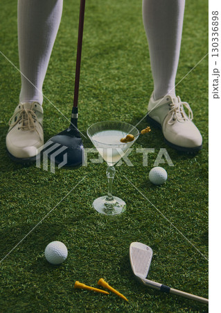 Golfer shoes and club with martini cocktail on grass 130336898
