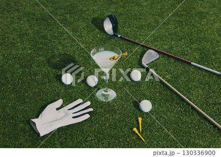 Golf martini cocktail with clubs balls and glove on green grass Golf martini cocktail with clubs balls and glove on green grass 130336900