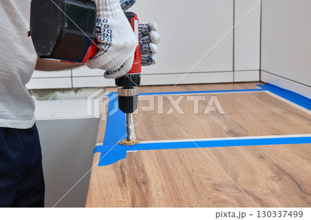 repairman using electric drill and installation new modern kitchen 130337499