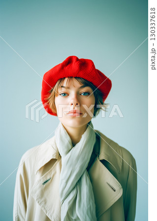 A woman wearing a red hat and scarf stands in front of a blue wall 130337618