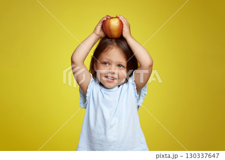 cute Caucasian little child girl holding apple on yellow background cute Caucasian little child girl holding apple on yellow background 130337647