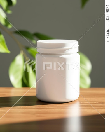 Minimalist White Supplement Bottle on Wooden Surface with a Green Plant Backdrop 130339874