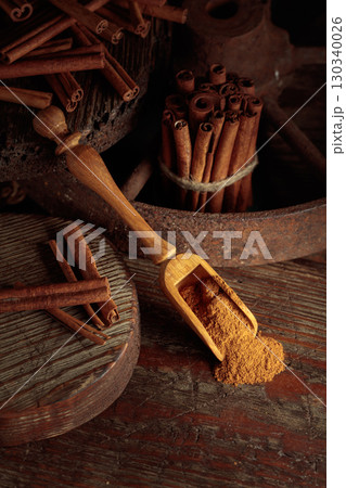 Wooden spoon with cinnamon powder and cinnamon sticks. Wooden spoon with cinnamon powder and cinnamon sticks. 130340026