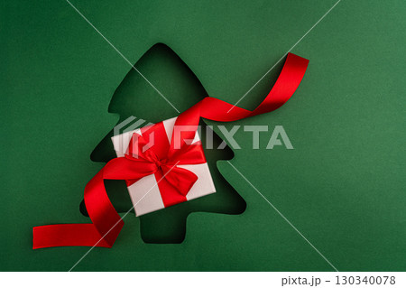 Christmas Gift Box with Red Ribbon in Tree Cutout Design 130340078