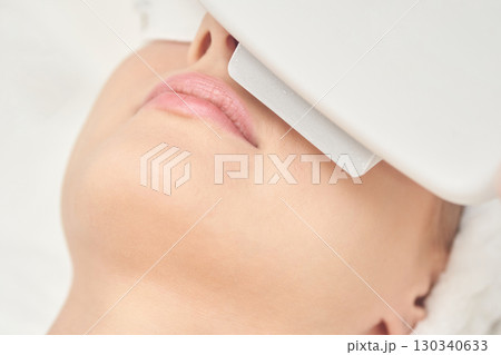 Caucasian female undergoing facial skin treatment with advanced beauty equipment 130340633