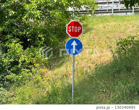 Road signs with stop and direction arrow near greenery. Transportation, safety, and urban regulation. Road signs with stop and direction arrow near greenery. Transportation, safety, and urban regulation. 130340995