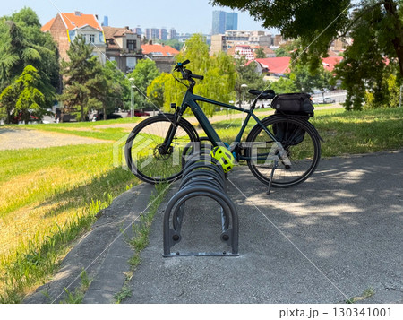 Bicycle parked outdoors with helmet on a stand. Urban mobility, active lifestyle and eco-friendly transport. 130341001