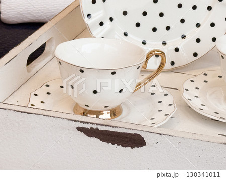Stacked cups and saucers with floral and decorative details on a white tray. Kitchenware, domestic life and home decor aesthetics. 130341011