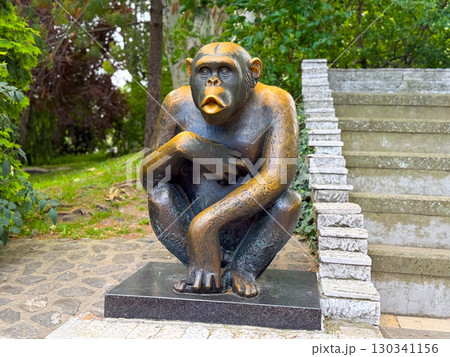 Statue of a monkey near stone stairs. Art, symbolism, and cultural representation of animals. 130341156