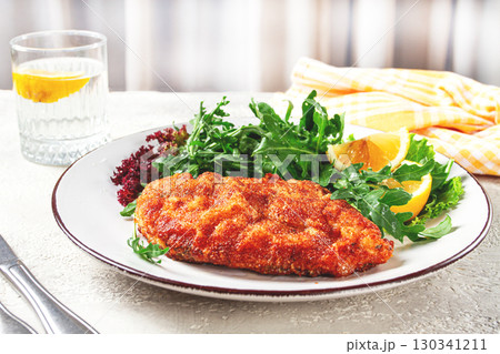 Milanese chicken, Crispy breaded chicken served, with fresh herbs, and lemon wedges, Milanese chicken, Crispy breaded chicken served, with fresh herbs, and lemon wedges, 130341211