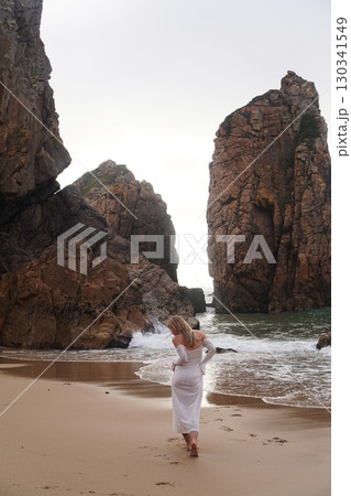 In Solitude by the Ocean A Woman Walking Alone Peacefully on the Beautiful Scenic Beachside 130341549