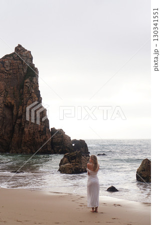 In Solitude by the Ocean A Woman Walking Alone Peacefully on the Beautiful Scenic Beachside 130341551