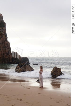 In Solitude by the Ocean A Woman Walking Alone Peacefully on the Beautiful Scenic Beachside 130341556