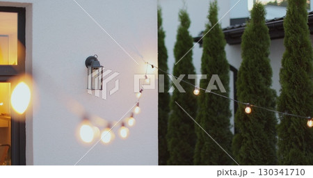 String lights hanging on line on outside house in backyard. Garden decoration. Party camping. 130341710