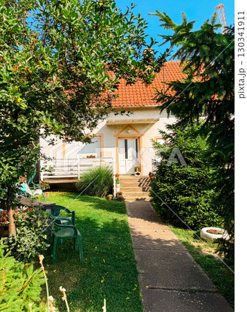 House with garden and green yard. Residential lifestyle, family environment, and suburban architecture with outdoor leisure space. 130341911