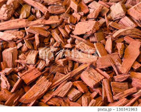 Red wood chips arranged as mulch creating a rough surface texture for landscaping and decoration. Organic recycling, natural material and environmental resource for gardening and ecological design. Red wood chips arranged as mulch creating a rough surface texture for landscaping and decoration. Organic recycling, natural material and environmental resource for gardening and ecological design. 130341963