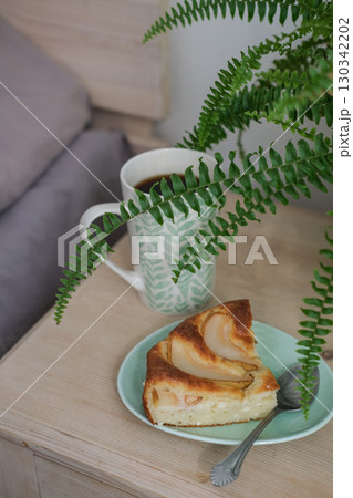 Slice of warm pear pie on plate, mug of coffee on nightstand. Perfect for showcasing relaxing morning or coffee break, as well as food blogs, lifestyle content or social media 130342202