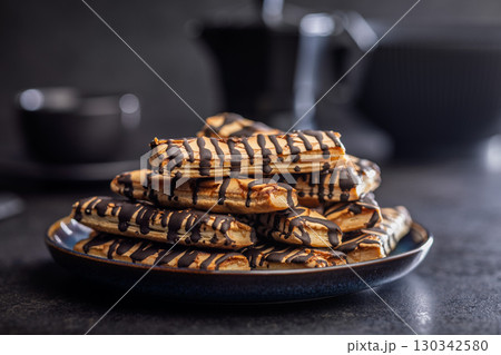 Sfogliatine glassate with chocolate. Italian crispy dessert on plate on black table. Sfogliatine glassate with chocolate. Italian crispy dessert on plate on black table. 130342580