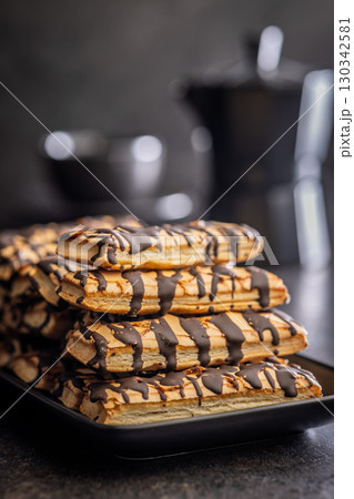 Sfogliatine glassate with chocolate. Italian crispy dessert on plate on black table. Sfogliatine glassate with chocolate. Italian crispy dessert on plate on black table. 130342581