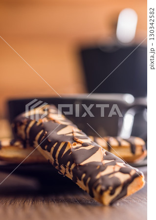 Sfogliatine glassate with chocolate. Italian crispy dessert on wooden table. Sfogliatine glassate with chocolate. Italian crispy dessert on wooden table. 130342582