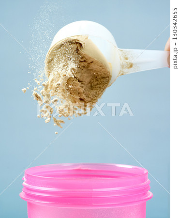 protein powder spills in cup from measure scoop. whey sports nutrition. dry mixture protein powder spills in cup from measure scoop. whey sports nutrition. dry mixture 130342655