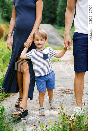 Smiling Child Holding Hands With Parents Outdoors Smiling Child Holding Hands With Parents Outdoors 130342704