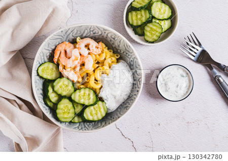 Bowl with pasta, shrimp, cucumber and sauce on the table top view 130342780