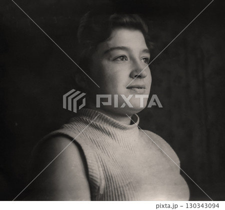 Vintage portrait of a beautiful young girl half-turned. Play of light and shadow. Retro photo 1956. 130343094