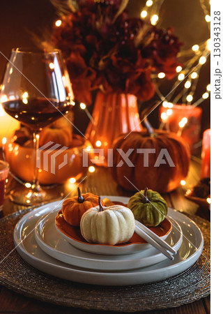 Autumnal table setting with decorative pumpkins, candles and string lights. 130343128