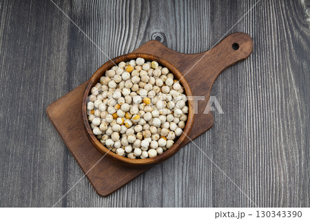 Roasted white chickpeas in wooden bowl on wooden background, top view. White chickpeas, with their high fiber content, are very healthy to consume. 130343390