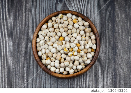 Roasted white chickpeas in wooden bowl on wooden background, top view. White chickpeas, with their high fiber content, are very healthy to consume. 130343392