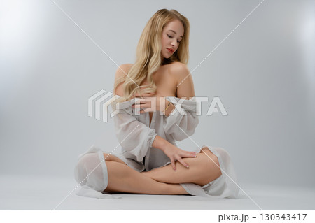 Captivating blonde woman poses gracefully in a studio setting 130343417