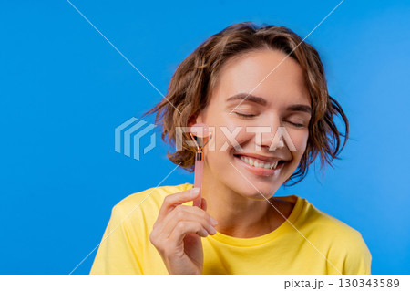 Charming Woman Doing Face Massage With Rose Quartz Stone Roller For Firmer Skin Charming Woman Doing Face Massage With Rose Quartz Stone Roller For Firmer Skin 130343589