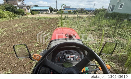 トラクター運転席から撮影、草の畑を耕す 130343619