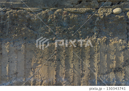 Weathered Cheap Uneven Concrete Surface with Pebbles under tangential harsh light 130343741
