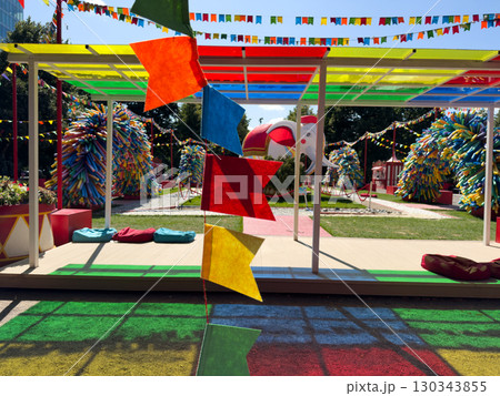 Colorful outdoor festival decoration with multicolored flags, creative playground design and bright summer atmosphere suitable for family celebration and cheerful event advertising Colorful outdoor festival decoration with multicolored flags, creative playground design and bright summer atmosphere suitable for family celebration and cheerful event advertising 130343855