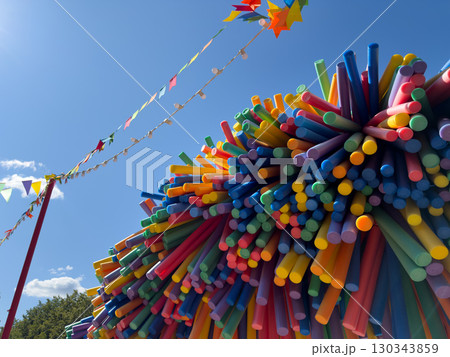 Abstract outdoor installation with colorful tubes against blue sky creating vibrant festive atmosphere and bright background suitable for design projects and creative concepts Abstract outdoor installation with colorful tubes against blue sky creating vibrant festive atmosphere and bright background suitable for design projects and creative concepts 130343859