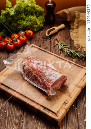 Fresh raw pork meat vacuum-sealed on wooden cutting board, perfect for cooking and meal preparation Fresh raw pork meat vacuum-sealed on wooden cutting board, perfect for cooking and meal preparation 130344370