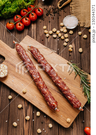 Rustic cured sausages with hazelnuts, garlic, and rosemary on wooden cutting board Rustic cured sausages with hazelnuts, garlic, and rosemary on wooden cutting board 130344371