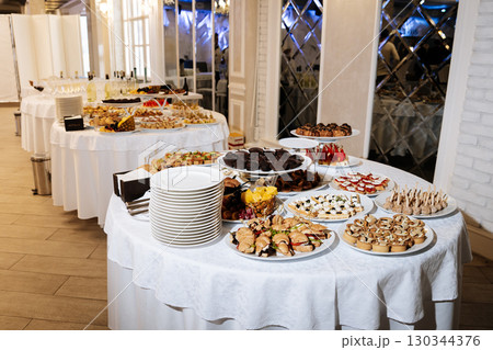 Elegant buffet table with gourmet canapes, desserts and fruit at festive banquet event Elegant buffet table with gourmet canapes, desserts and fruit at festive banquet event 130344376