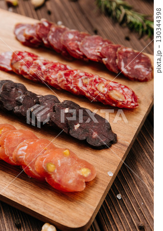 Close-up of gourmet sliced sausage with nuts on wooden board, traditional cured meat snack Close-up of gourmet sliced sausage with nuts on wooden board, traditional cured meat snack 130344398