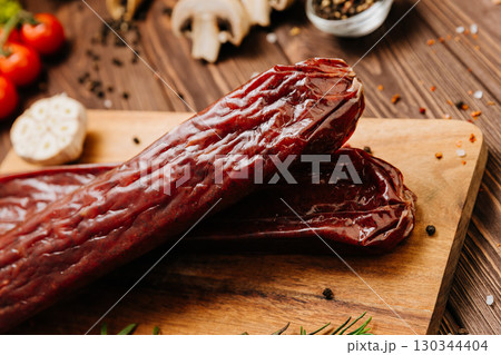 Smoked salami sticks on a wooden board, perfect for charcuterie boards and gourmet presentations 130344404