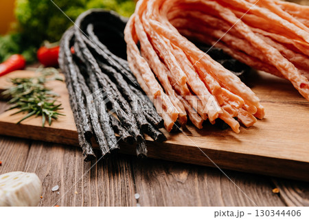 Variety of black and light meat sticks on board with herbs and spices, ideal for culinary display 130344406