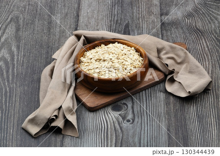 Oat flakes uncooked in a brown bowl on wooden table. Healthy food for breakfast 130344439