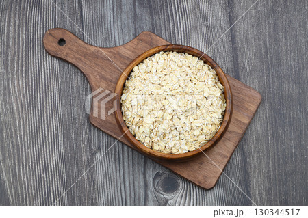 Oat flakes uncooked in a brown bowl on wooden table. Healthy food for breakfast 130344517